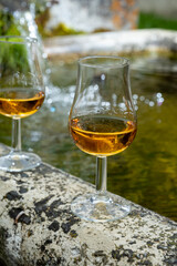 Glasses of strong scotch single malt whisky served on old stone reservoir for water from mountain spring