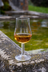Glass of strong scotch single malt whisky served on old stone reservoir for water from mountain spring