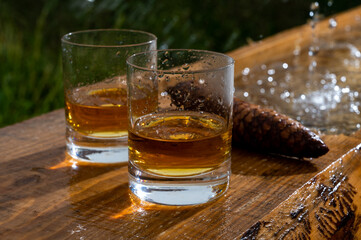 Glasses of strong scotch single malt whisky and rain water drops