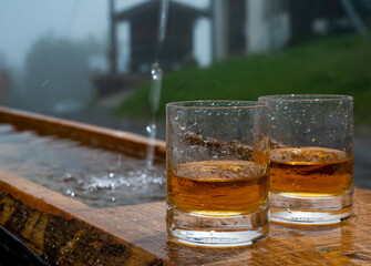 Glasses of strong scotch single malt whisky and rain water drops