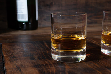 Glasses of strong scotch single malt whisky served on dark wooden table in old pub