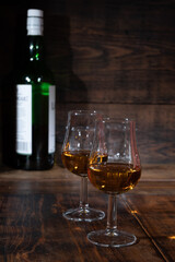 Glasses of strong scotch single malt whisky served on dark wooden table in old pub