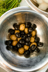 top view of green and black olives in a metal bowl