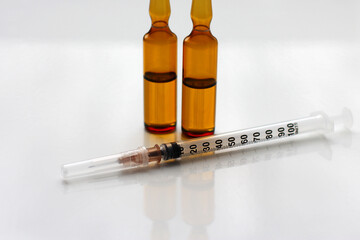 A syringe and glass ampoules with a medicine or chemical reagent on the table. The concept of a...