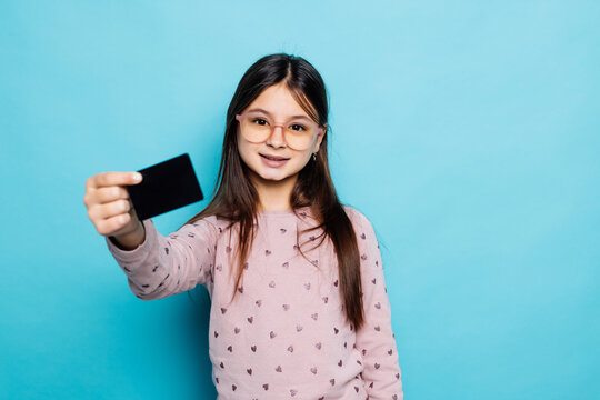 Photo of surprised cheerful teen girl hold bank card wear casual outfit isolated on blue color background