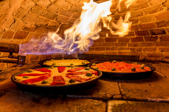 Pizzas de mozzarella morron clay oven with flame on wood