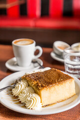 bread pudding with cream with coffee on wood