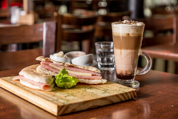breakfast sandwich ham and cheese with coffee with chocolate milk on wood