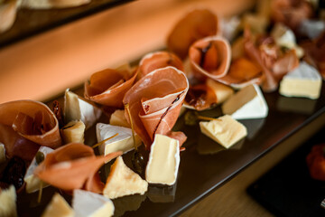 Close-up of sliced pieces of delicious brie cheese and thin slices of prosciutto and salami