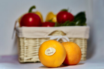 CO2 neutral label on oranges. Carbon labeling. Net zero carbon, emissions free. Wicker basket with carbon neutral product label on fresh vegetables. Organic farm products from local market.