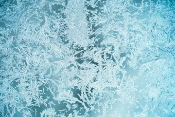 Fototapeta na wymiar The texture is frozen glass, the background of the frost pattern is blue. Snowflakes on the glass