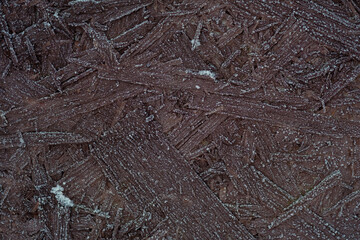 Background of brown wooden osb panels covered with snow and ice