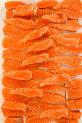 Top view of many pieces of fresh raw salmon fillet on parchment