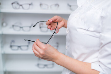 Optician, optometrist, oculist or eye doctor holding glasses and specs with new lenses. Professional eyesight specialist in clinic or shop with spectacles in hand. Bifocal or multifocal eyeglasses