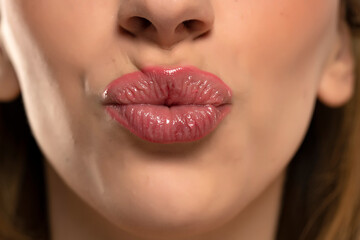 Beautiful puffy feminine lips with kissing gesture and nude lipstick