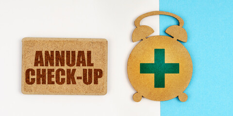 On the white and blue surface are an alarm clock and a sign with the inscription - ANNUAL CHECK-UP