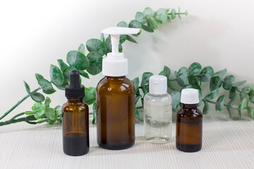 Various glass bottles for cosmetics, essential oils or other liquids on a white background with eucalyptus branch.