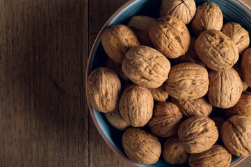 Walnuts in a ceramic bowl on a dark wooden background