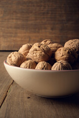 Walnuts in a ceramic bowl on a dark wooden background