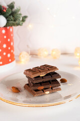 Natural organic pieces of chocolate bars with nuts on white plate. Confectionery concept. Vertical orientation.