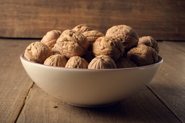 Walnuts in a ceramic bowl on a dark wooden background