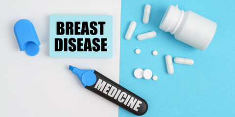 On the white and blue surface are pills, a marker and paper with the inscription - BREAST DISEASE