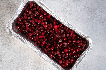 Frozen berries covered with hoarfrost. Frozen cowberries or lingonberries on grey background.