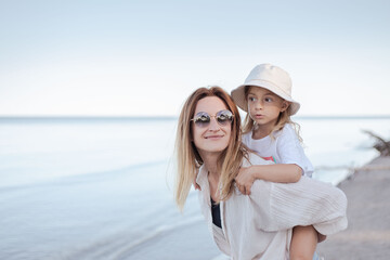 beautiful mom and her daughter at seaside smiling and have fun. Lovely family lifestyle concept.