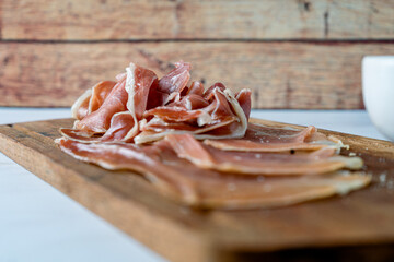 Arrangement of an exquisite Spanish serrano ham on a cutting board with olive oil and bread.. Normal view.