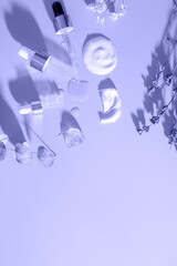 Smears of various cosmetic products and pipettes on very peri trendy color background with dry...