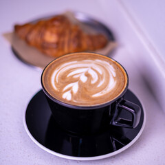 Hot coffee and croissants on a marble table.