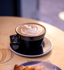 Cup of cappuccino coffee and beautiful heart Latte on wood bar