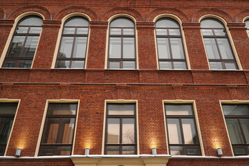 Fototapeta premium The wall of the house is made of red brick with windows