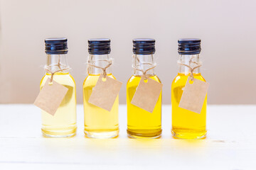Four types of unrefined oil in small bottles with a place for signature on the labels, on a light background. The concept of healthy eating