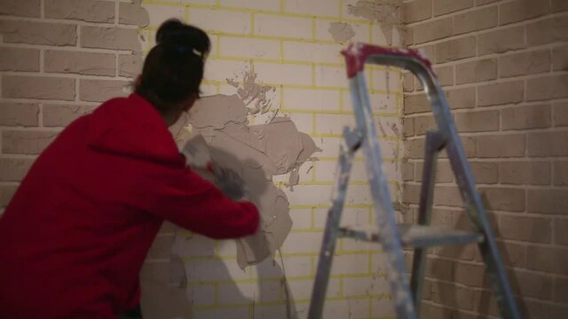 Imitation of stucco brickwork. Home renovation is a DIY made of construction mix and scotch tape. A woman puts mortar on the wall and makes fake bricks