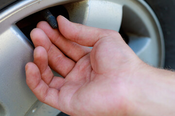 The hand twists or unscrews the nipple cap from the car wheel. Place the air replenishment tires.