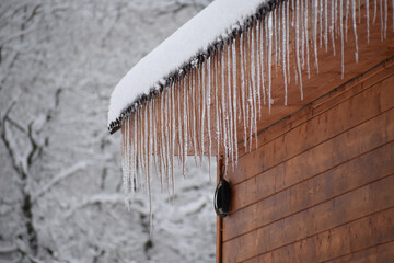 large ice icicles hang from  roof. ice falling hazard