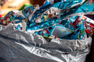 Discarded used wrapping paper in a trash bag after opening gifts .