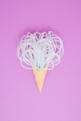 Shiny decorations in ice cream cone on bright pink background. Minimal concept. Flat lay.