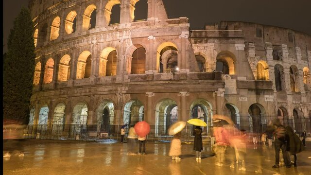 Time lapse of tourists taking picture near famous Roman monument Colosseo on a rainy evening. 