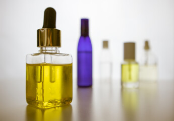 Silhouettes of small yellow and blue bottles with natural cosmetics, essential oil, face body skin care aroma oils on white background. Wellness, spa composition. Various capacities, limpid glassware.