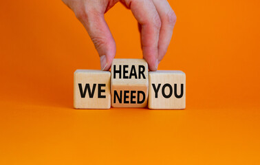 We need and hear you symbol. Businessman turns the wooden cube and changes words we need you to we...
