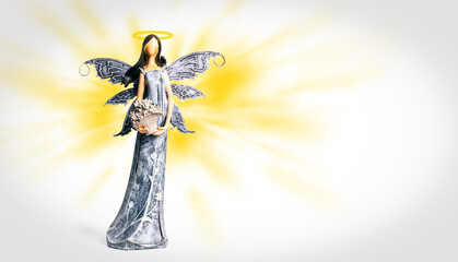 Angel with halo on yellow and white background. Statue of angel. Spiritual, faith, heaven. Guardian Angel on background with light rays of the sky and with copy space.