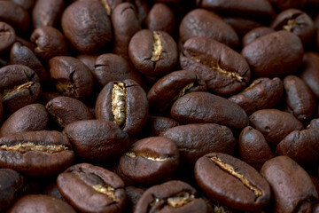 Roasted coffee beans scattered in random order on a dark background