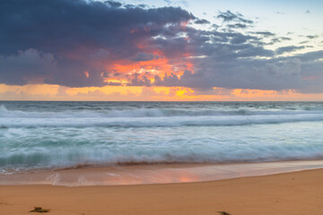 Sunrise at the seaside with waves and clouds