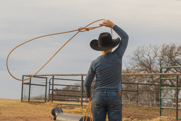 young boy swinging a rope at a roping dummy  - obrazy, fototapety, plakaty