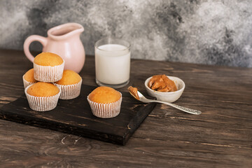 Freshly baked fresh muffins. jug and glass of milk on a wooden table. Portion cupcakes, sweet