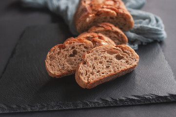 Baked homemade bread on wooden table with a gray gauze tablecloth