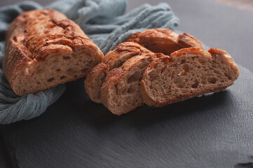 Sliced bread on a wooden table with a gray gauze tablecloth