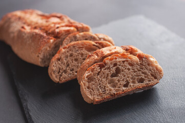 Rustic bread, beautiful golden crust, sliced bread lying on black board